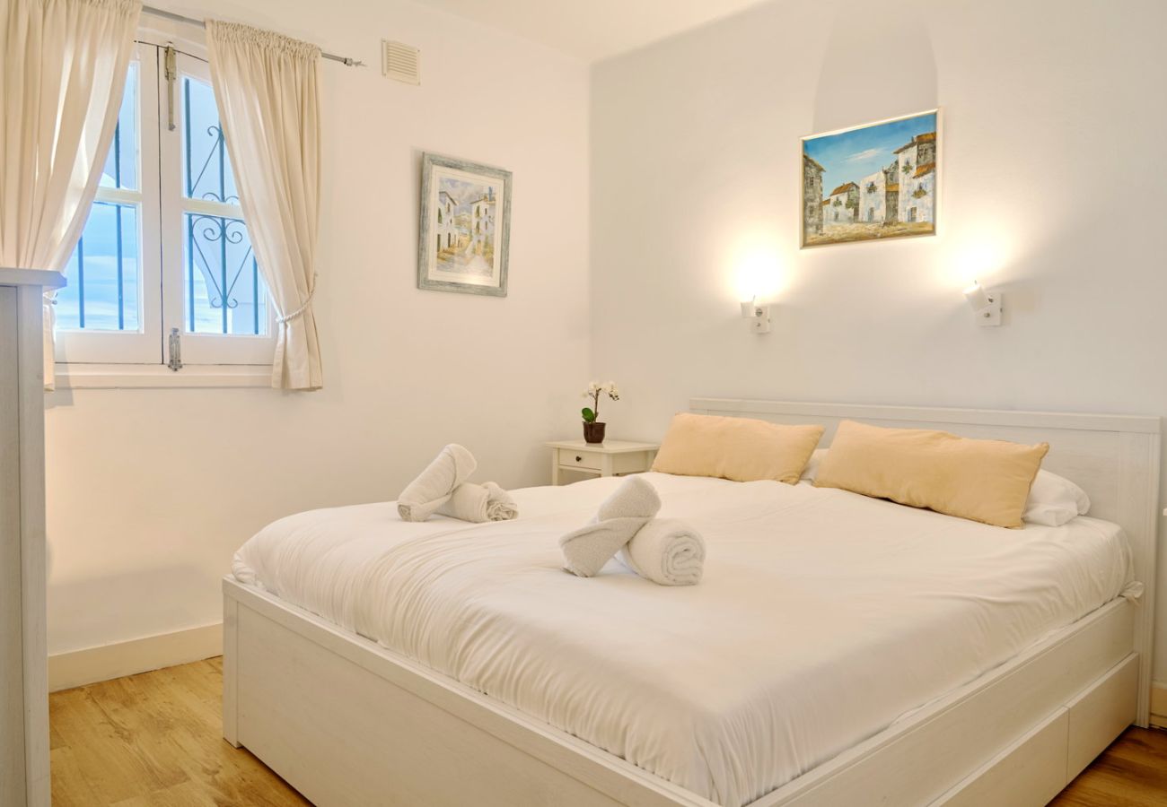 Hoofdslaapkamer met tweepersoonsbed en natuurlijk licht in vakantieappartement.