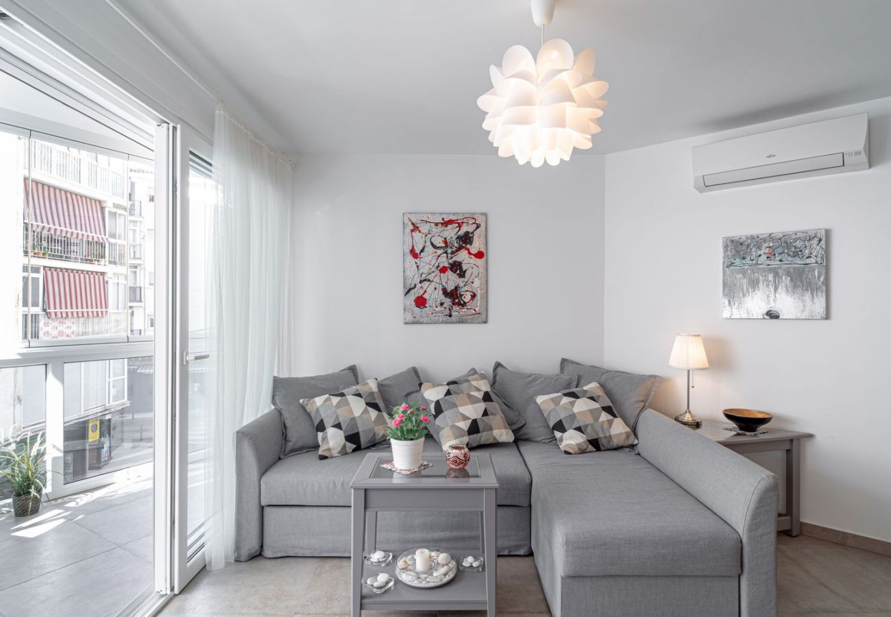 Lichte woonkamer met designbank en directe toegang tot het glazen balkon in Nerja centrum.